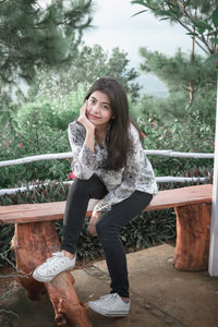 Portrait of smiling young woman against trees