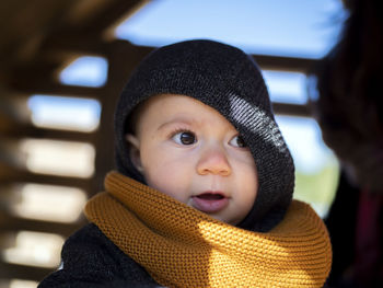 Close-up of cute girl wearing sweater and knit hat sitting at home