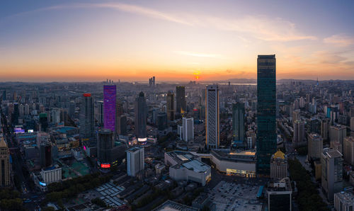 Aerial view of modern buildings in city against sky during sunset