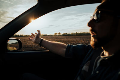 Portrait of man driving car against sky