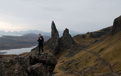 Rear view of man standing on mountain against sky