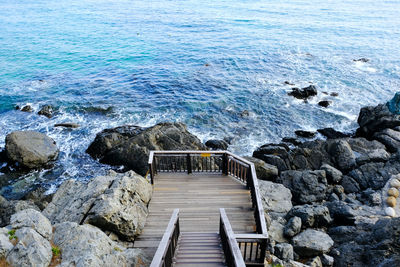 High angle view of steps by rock formation against sea