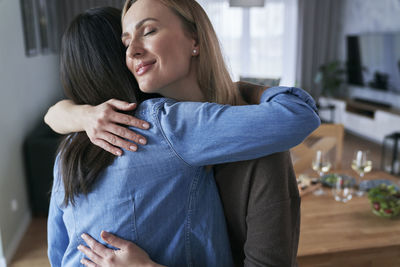 Female friends embracing at home