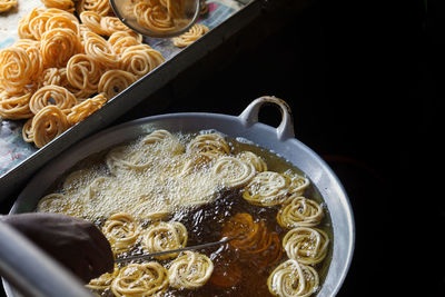 Cropped hand of person frying food in cooking utensil