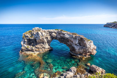 Panoramic view of rock formation in sea against sky