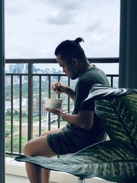 Side view of young man sitting on chair at home