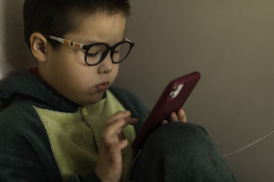 Closeup portrait of boy who looks into the phone sitting on the floor, playing on phone on charging