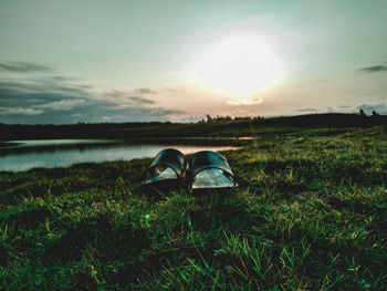 Sunglasses on field against sky during sunset