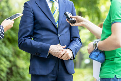 Midsection of man holding camera while standing outdoors