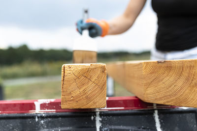 The woman impregnates raw planed wooden pine beams with dimensions of 100mm colorless impregnation.