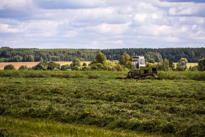 Agricultural tractor on field against sky at summer daylight