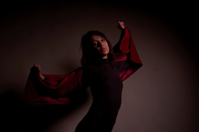 Young woman standing against red background