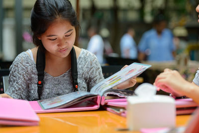 Midsection of woman reading book on table