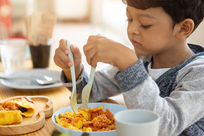 Close-up of boy eating food sitting at restaurant