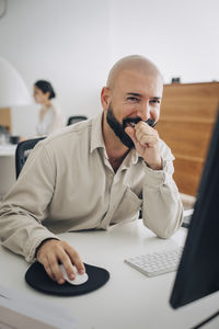 Portrait of happy male entrepreneur sitting at desk in office