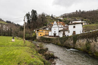 Houses by river and buildings against sky