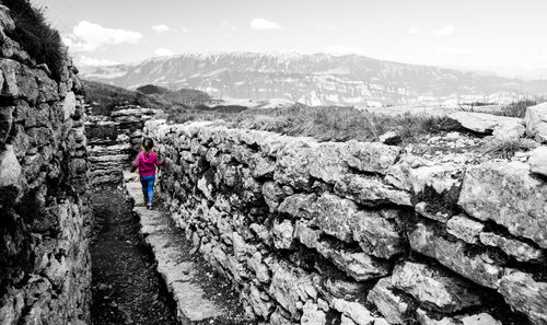 Full length of woman standing on rock against sky