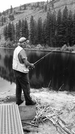 Full length of man looking at lake against trees