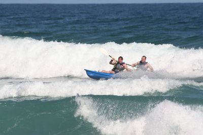 People surfing in sea against clear sky