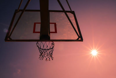 Low angle view of basketball hoop against sky during sunset