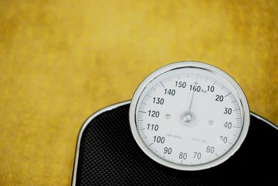 Close-up of weight scale on yellow background