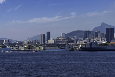 Sea by buildings against sky in city