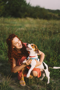 Beautiful woman plays with her jack russell dog in the park.