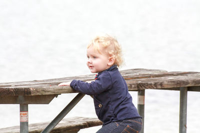 Side view of boy looking at railing against water