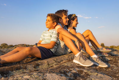 Three kids with on a top of a rock on their summer vacation