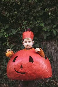 Boy wearing homemade pumpkin halloween costume and holding gourd