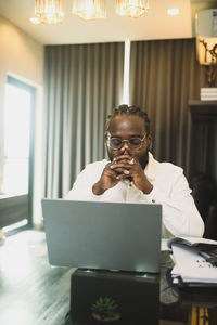 Man using laptop while sitting on table
