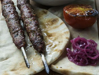 Close-up of fresh shish kebab lamb meat on skewers over flatbreads