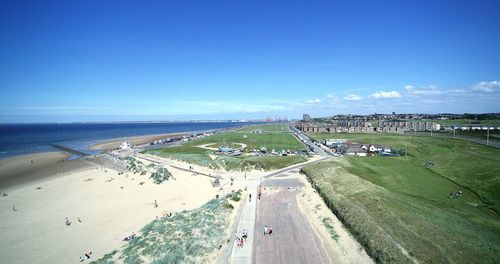 High angle view of road by sea against blue sky