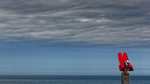 Red flag on sea against sky