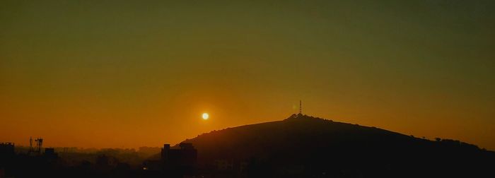 Silhouette temple against buildings during sunset