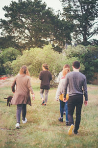 Rear view of people walking on grassland