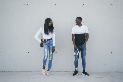 Portrait of young couple standing against wall