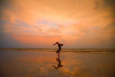 Man standing on beach against sky during sunset