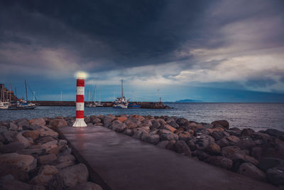 Lighthouse by sea against sky