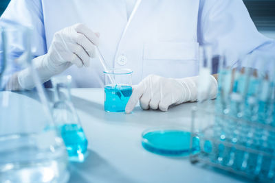 Midsection of scientist examining chemical in laboratory