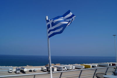 Flag by sea against clear blue sky