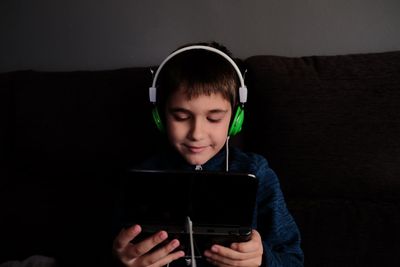 Boy looking at camera while sitting on sofa at home