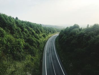 High angle view of empty road amidst trees against sky