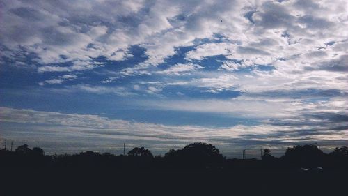 Silhouette of trees against cloudy sky