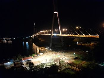 Illuminated bridge over river against sky at night