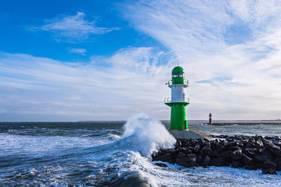 Lighthouse by sea against sky