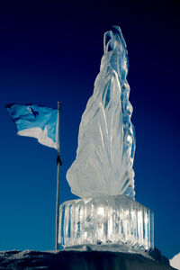 Low angle view of statue against clear blue sky during winter