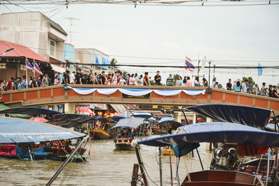 People walking on bridge over boats in river