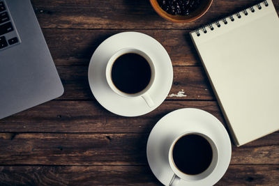 Directly above shot of coffee cups with laptop on table