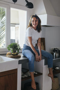 Woman sitting on kitchen worktop barefoot
